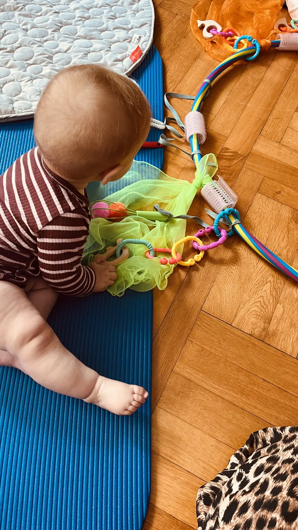Mama liegt auf der Matte und hebt ihr lachendes Baby über sich