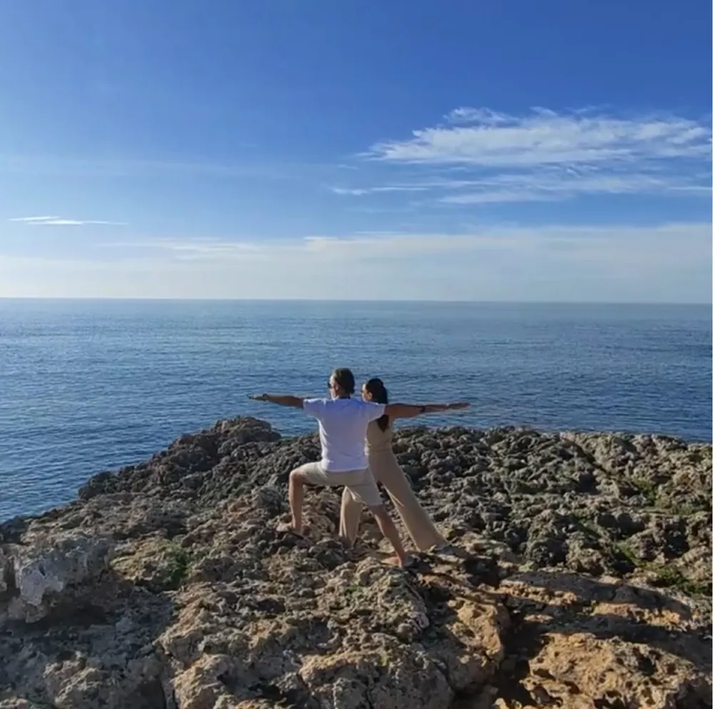 Zwei Menschen in einer Yogapose auf einem Felsen an der Küste